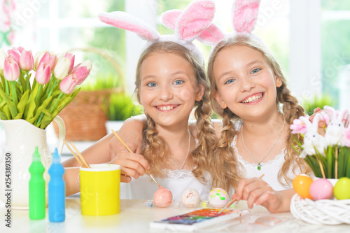 Portrait of cute twins wearing rabbit ears decorating Easter eggs