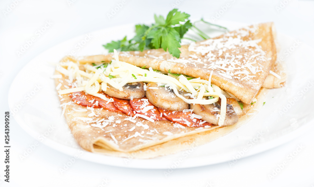 Thin delicious pancake with salami and mushrooms on white Thin delicious pancake with salami and mushrooms on white