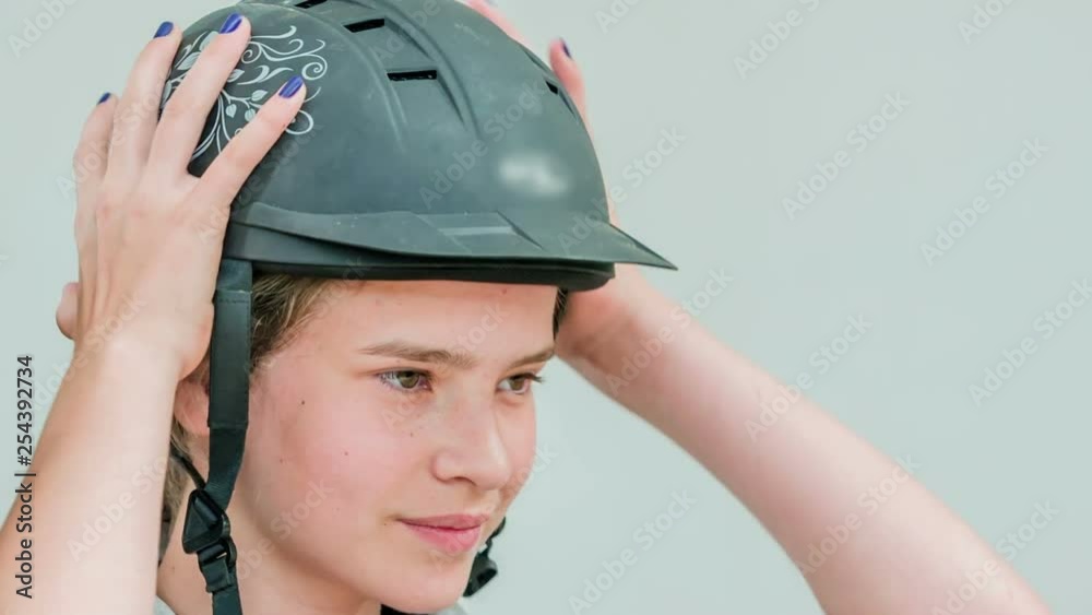 A young girl puts on a security helmet before going out for a ride with her beautiful brown horse. A young girl puts on a security helmet before going out for a ride with her beautiful brown horse.