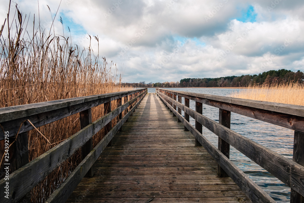Naklejka premium wooden pier at waterside - straight wood dock walkway at lake
