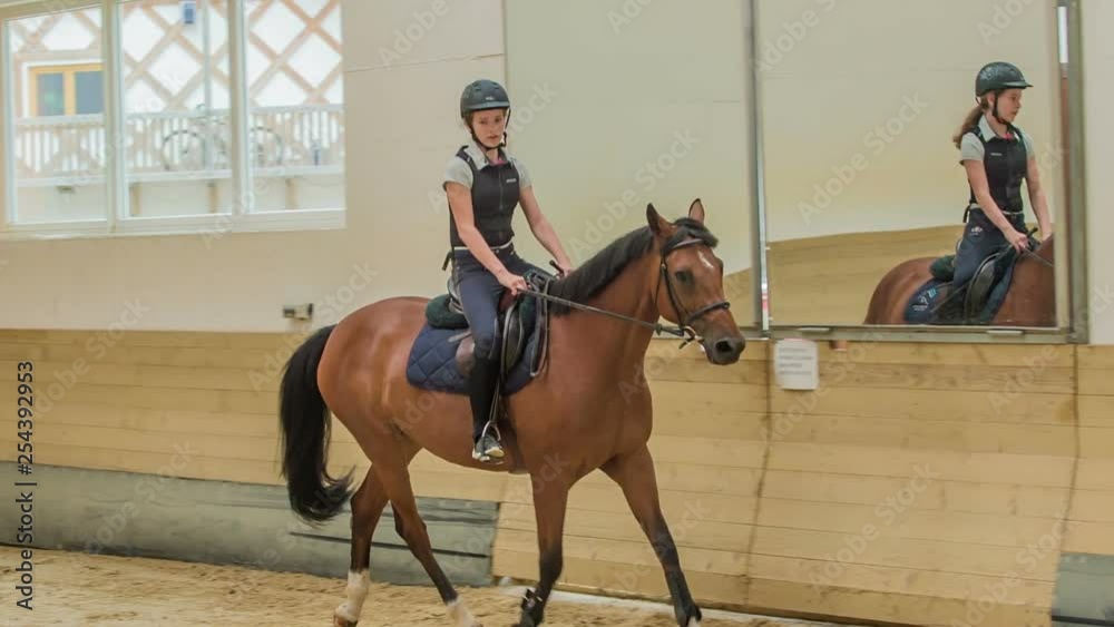 A beautiful and talented young girl during her riding session in a closed horse arena. A beautiful and talented young girl during her riding session in a closed horse arena.