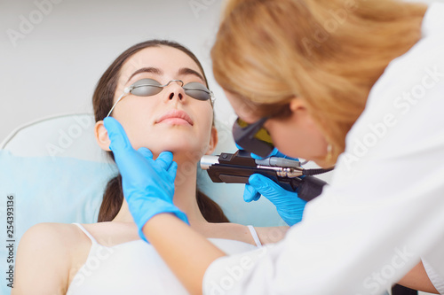 Laser hair removal on the face of a young woman in a cosmetology