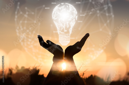 The abstract image of the hand hold the illumination lamp during sunrise overlay with futuristic hologram. the concept of communication, idea, futuristic, internet of things and technology.