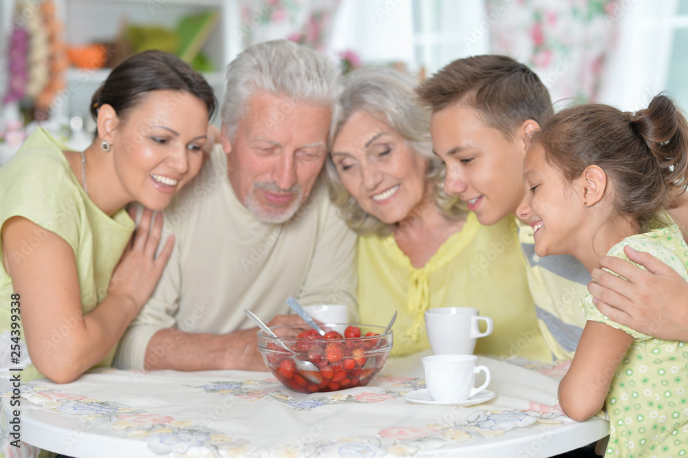 Portrait of big happy family eating fresh strawberries at kitchen