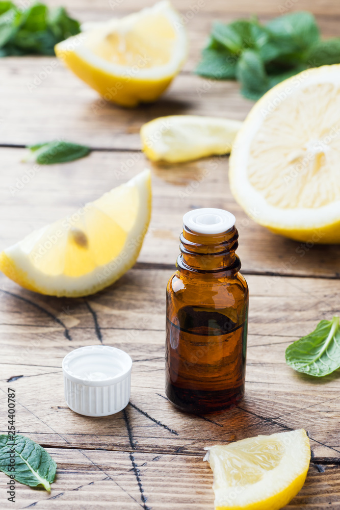 Essential lemon oil in bottle, fresh fruit slices on wooden background. Natural fragrances. Essential lemon oil in bottle, fresh fruit slices on wooden background. Natural fragrances.