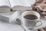 a cup of hot coffee and books on wooden table, hot drink for winter
