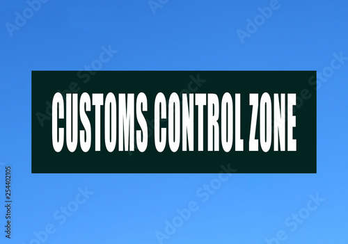 A green sign with an inscription in English: "Customs control zone" against a blue sky. Storage customs clearance.