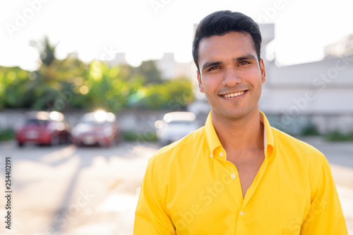 Happy young handsome Indian man smiling in the streets outdoors
