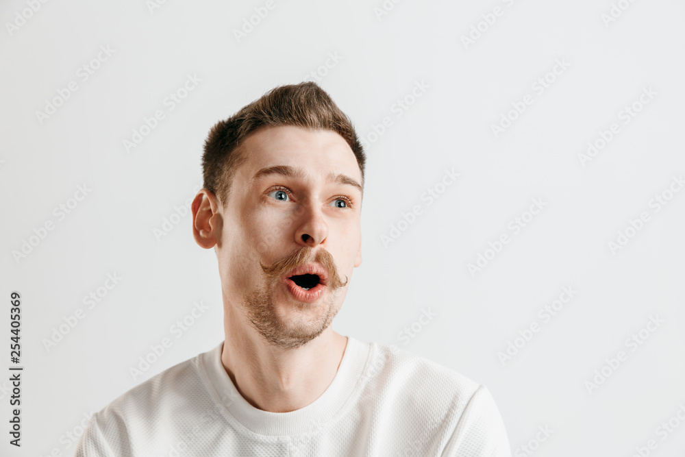 Wow. Attractive male half-length front portrait on gray studio backgroud. Young emotional surprised bearded man standing with open mouth. Human emotions, facial expression concept Wow. Attractive male half-length front portrait on gray studio backgroud. Young emotional surprised bearded man standing with open mouth. Human emotions, facial expression concept