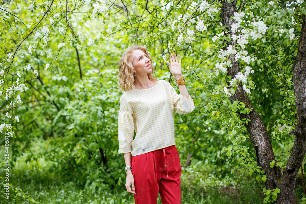 Woman in a light jumper on the street in spring in blooming apple trees Woman in a light jumper on the street in spring in blooming apple trees