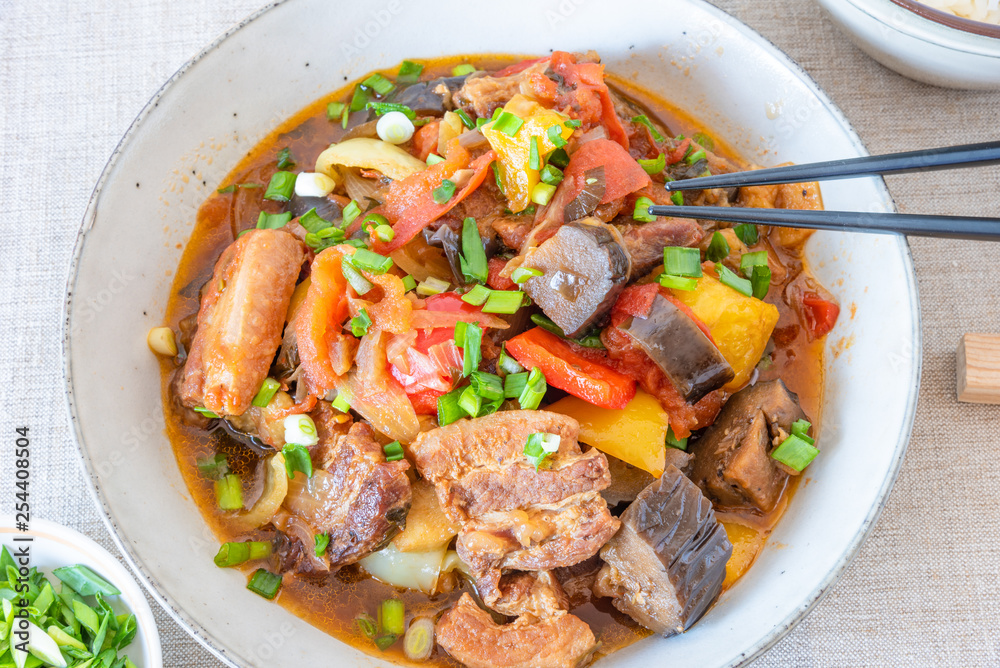 Fried pork with eggplants and sweet peppers in a large bowl - a traditional Chinese dish Fried pork with eggplants and sweet peppers in a large bowl - a traditional Chinese dish