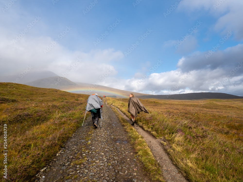 a man and a woman hiking with rainbow