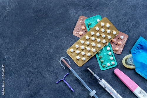 Choosing method of contraception : Birth control pills, an injection syringe, condom, IUD-method, on grey photo