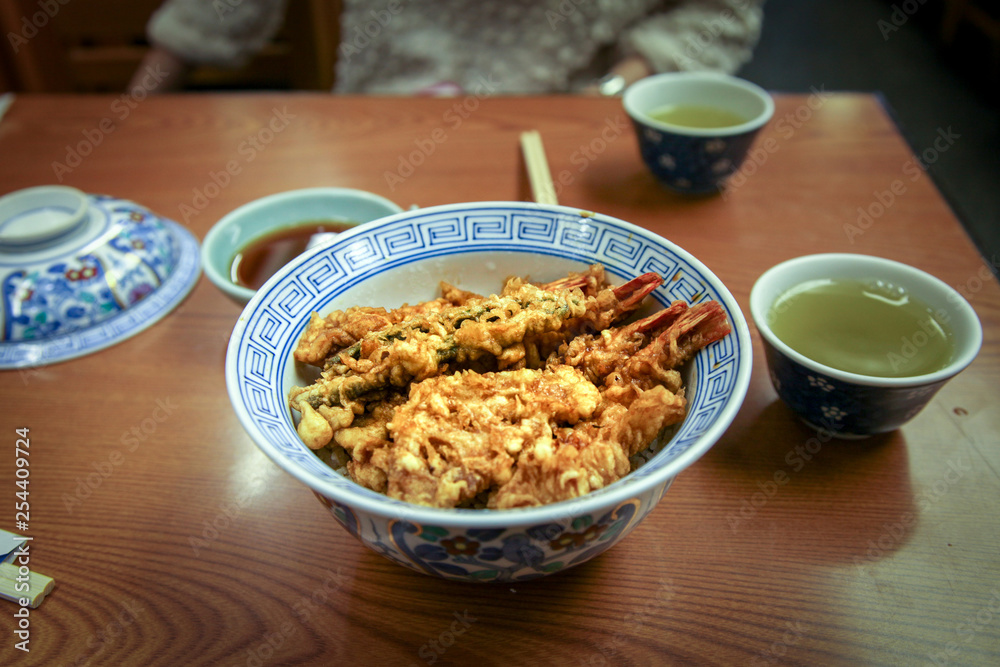 Tempura Donburi or ten don japanese shrimp and vegetables tempura on rice with sauce on the table . Tempura Donburi or ten don japanese shrimp and vegetables tempura on rice with sauce on the table .