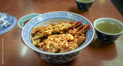 Tempura Donburi or ten don japanese shrimp and vegetables tempura on rice with sauce on the table .