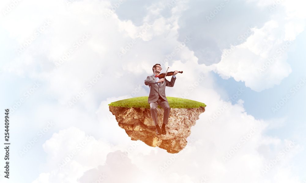Handsome violinist on floating island in blue sky play his melody Handsome violinist on floating island in blue sky play his melody