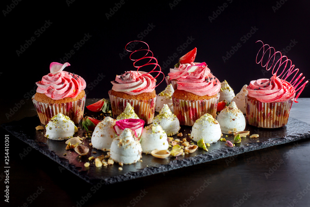 Cupcakes with pink cream, meringues sprinkled with nuts.
