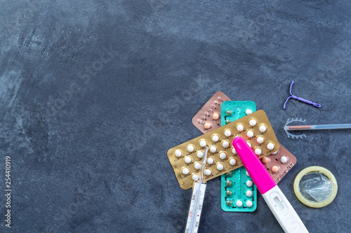 Choosing method of contraception : Birth control pills, an injection syringe, condom, IUD-method, on grey photo