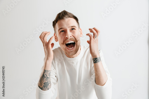 Screaming, hate, rage. Crying emotional angry man screaming on gray studio background. Emotional, young face. male half-length portrait. Human emotions, facial expression concept.