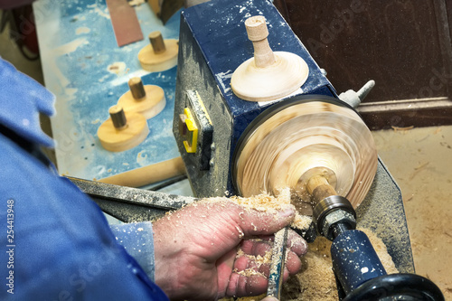 Work carpenter on a lathe on a tree. Close-up of a man's hands with a chisel during the processing of a wooden blank.