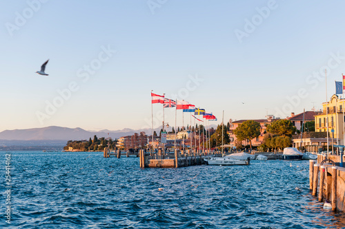 Sunset with red-yellow sun on a lake or sea. Sky, shore, sun and water. Flags of different cities, countries and territories. Free space for text. photo