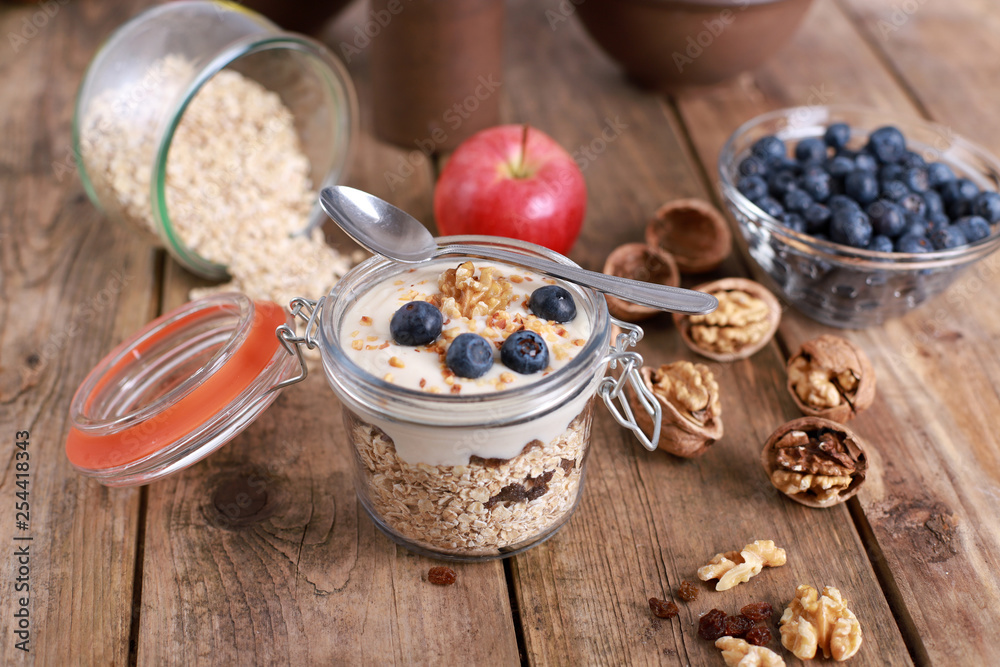 light healthy breakfast with yogurt on oatmeal muesli , blueberries and walnuts in a glas on a rustic wooden table light healthy breakfast with yogurt on oatmeal muesli , blueberries and walnuts in a glas on a rustic wooden table