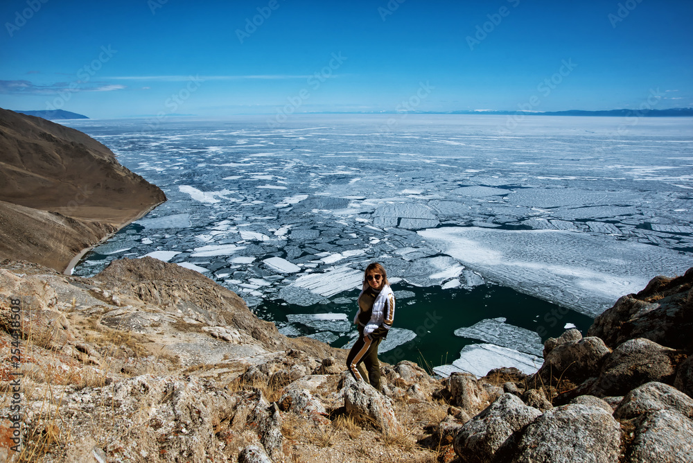 View above big beautiful lake Baikal with Ice floes floating on the water with girl wears white jacket, Russia View above big beautiful lake Baikal with Ice floes floating on the water with girl wears white jacket, Russia