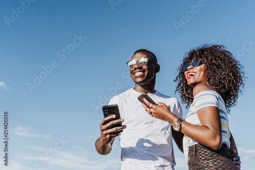 Two happy friends using the mobile in the street. Friendship concept. photo
