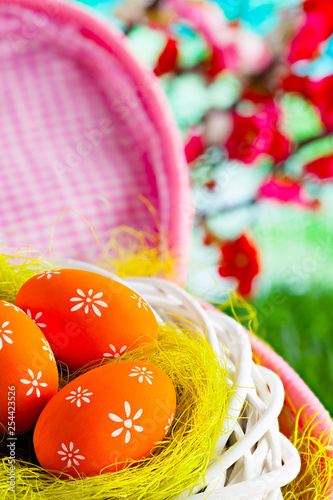 Easter eggs in the nest and pink basket on nature background
