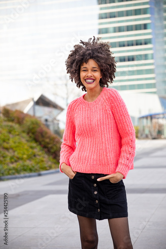 Beautiful young girl with curly brown hair with pink sweater in town