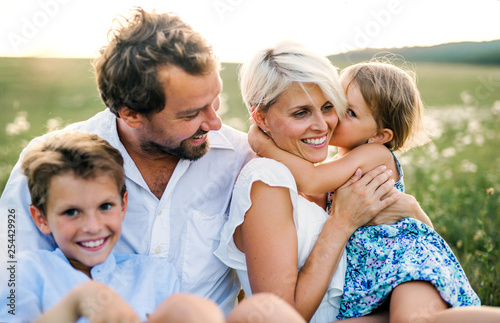 Young family with small children in summer nature at sunset.