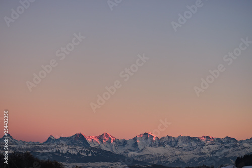 Colorful evening sky gradient with fameous jungfrau mountain range seen from the little mountain (Gurten) in Bern (Eiger, Mönch and Jungfrau). Sunset light reaches only peaks.