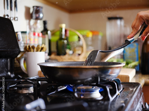 Foto stirring strips of beef in hot skillet inside home kitchen on gas stove