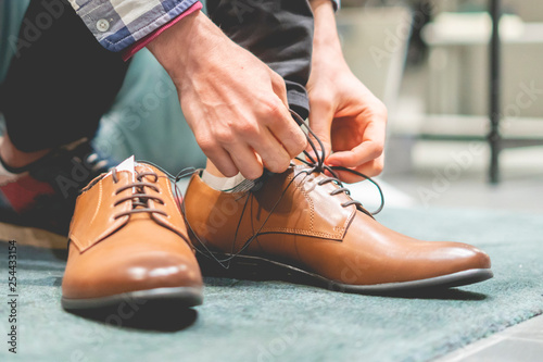 elegant businessman try on new brown classic shoes