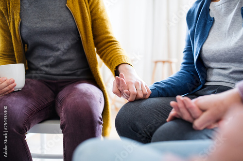 Fototapeta Naklejka Na Ścianę i Meble -  Midsection of men and women sitting in a circle during group therapy.