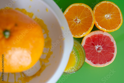 Juice for breakfast. Squeezing grapefruit and orange on green background
