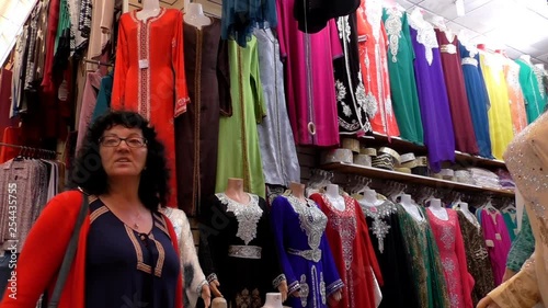 European woman tourist looking at Muslim style dresses in the Morocco market 