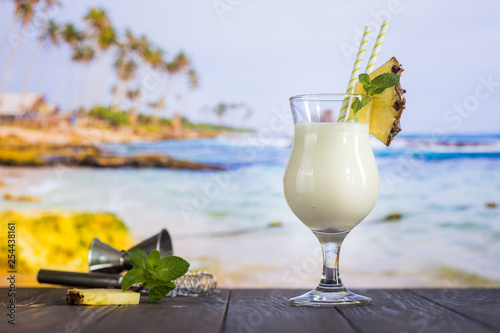 Cold pina colada cocktail in a glass on the beach with seascape background