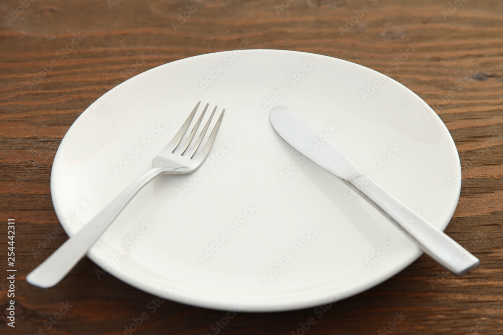 white dish on the brown table with cutlery meaning PAUSE white dish on the brown table with cutlery meaning PAUSE