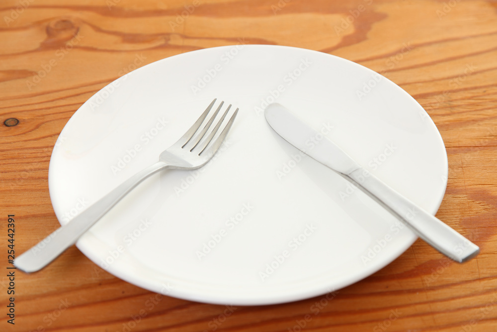 white dish on the wooden table with cutlery meaning PAUSE white dish on the wooden table with cutlery meaning PAUSE