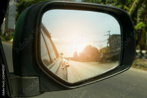 Traveling on the road, view from the side mirror with orange light.In the country.