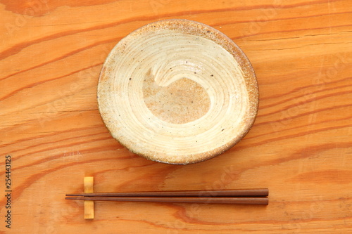 empty clay dish with chopsticks on the wooden table
