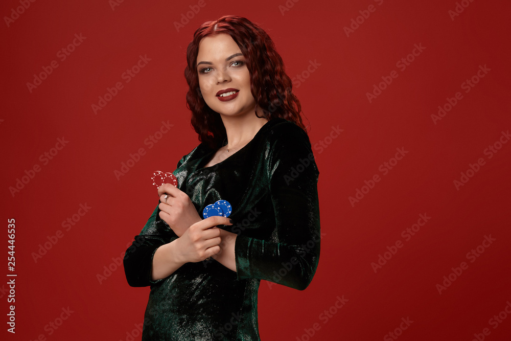 Lucky redheaded woman holding some gambling chips in her hands on a red background. Lucky redheaded woman holding some gambling chips in her hands on a red background.