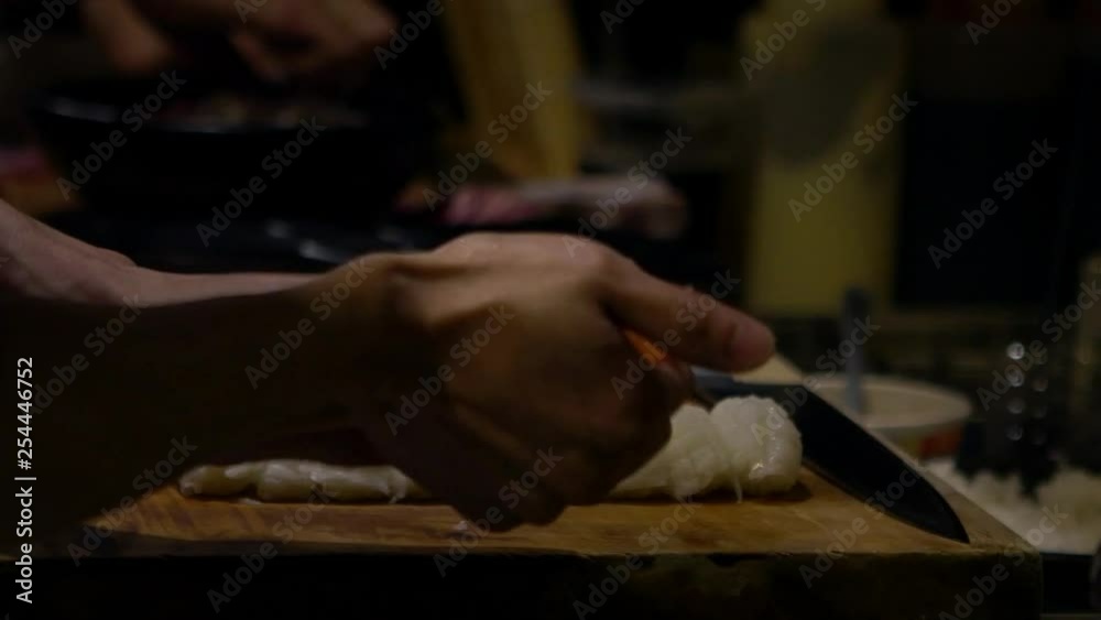 Asian cheff prepare the slice of raw fish for make a sushi in a kitchen of Japan. Man cooking in a japanese restaurant. Close up of hands making delicious asiatic food for sale-Dan Asian cheff prepare the slice of raw fish for make a sushi in a kitchen of Japan. Man cooking in a japanese restaurant. Close up of hands making delicious asiatic food for sale-Dan