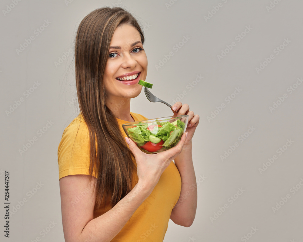 girl wearing yellow T-shirt eating salad with lettuche from glass bowl. isolated studio portrait. girl wearing yellow T-shirt eating salad with lettuche from glass bowl. isolated studio portrait.