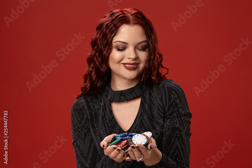 Beautiful redheaded woman is holding some gambling chips. Casino