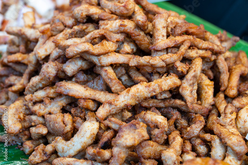 Deep fried merinated pork is great to have. The finger snack is one of the favourite street food available in all Thai market ready-made meal stall, background blurred.