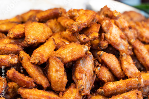 Deep fried chicken wings; The crispy small pieces of golden brown and tasty street food are on a white plate with background blurred.