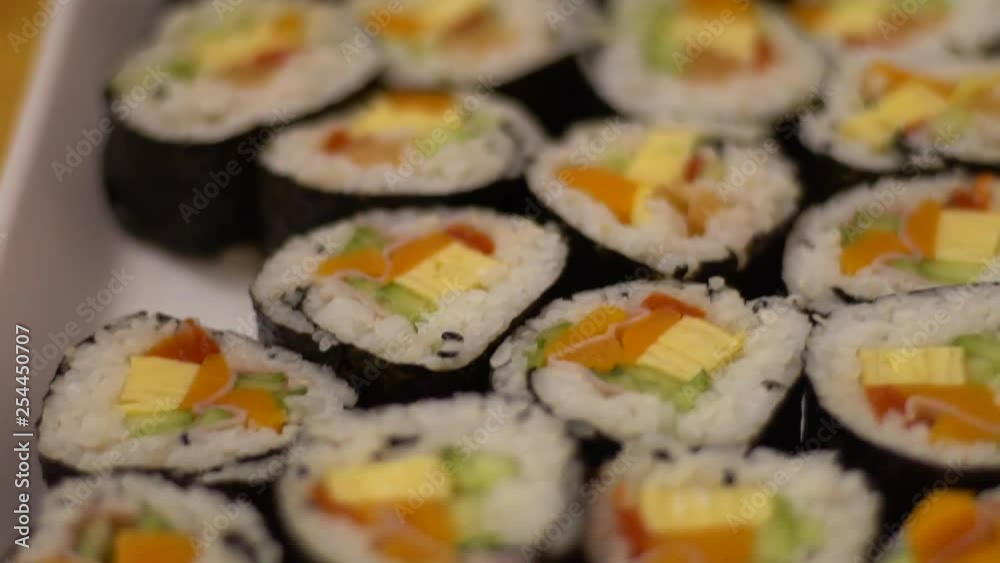 Slow Motion of delicious makizushi set with salmon served on white plate. Traditional rolled sushi Japanese food in restaurant. Nori roll with rice seeweed and fish in a gourmet menu.-Dan Slow Motion of delicious makizushi set with salmon served on white plate. Traditional rolled sushi Japanese food in restaurant. Nori roll with rice seeweed and fish in a gourmet menu.-Dan