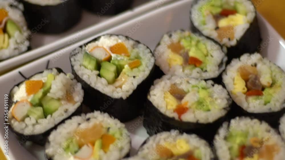 Slow Motion of delicious makizushi set with salmon served on white plate. Make homemade rolled sushi at home. Nori roll with rice seeweed and fish in a gourmet menu.-Dan